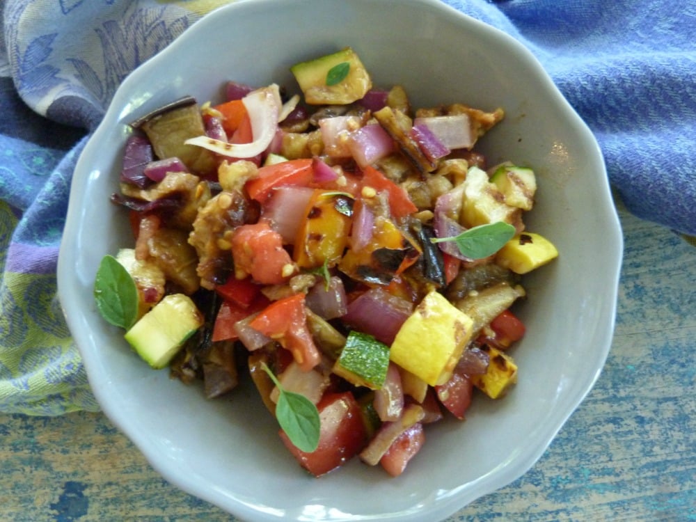 Small gray bowl filled with chopped up grilled eggplant, zucchini, summer squash, peppers and chopped tomatoes.