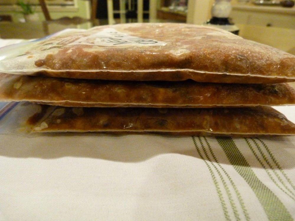 Zip top bags laying flat filled with chili to freeze.