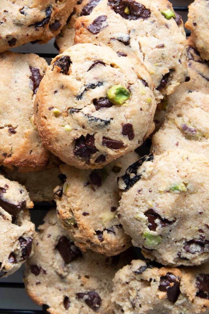 A pile of gluten-free vegan cookies with pistachios and chocolate chunks.
