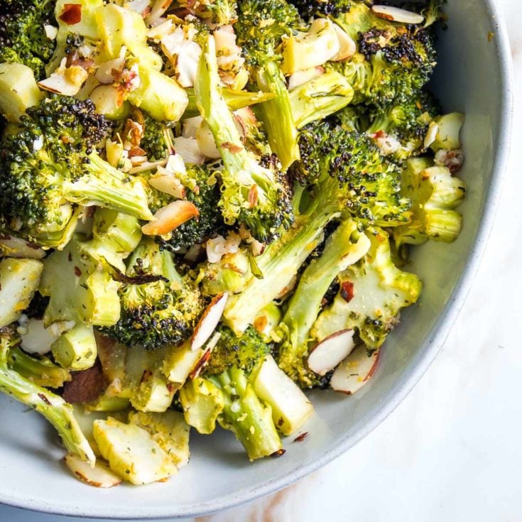 close up of a bowl of roasted broccoli with sliced almonds