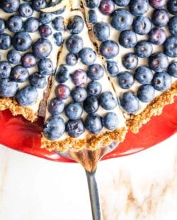 A slice of blueberry tart being served from a red cake plate.