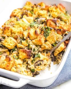 White casserole dish filled with cornbread stuffing, including mushrooms, kale, celery and fresh herbs.