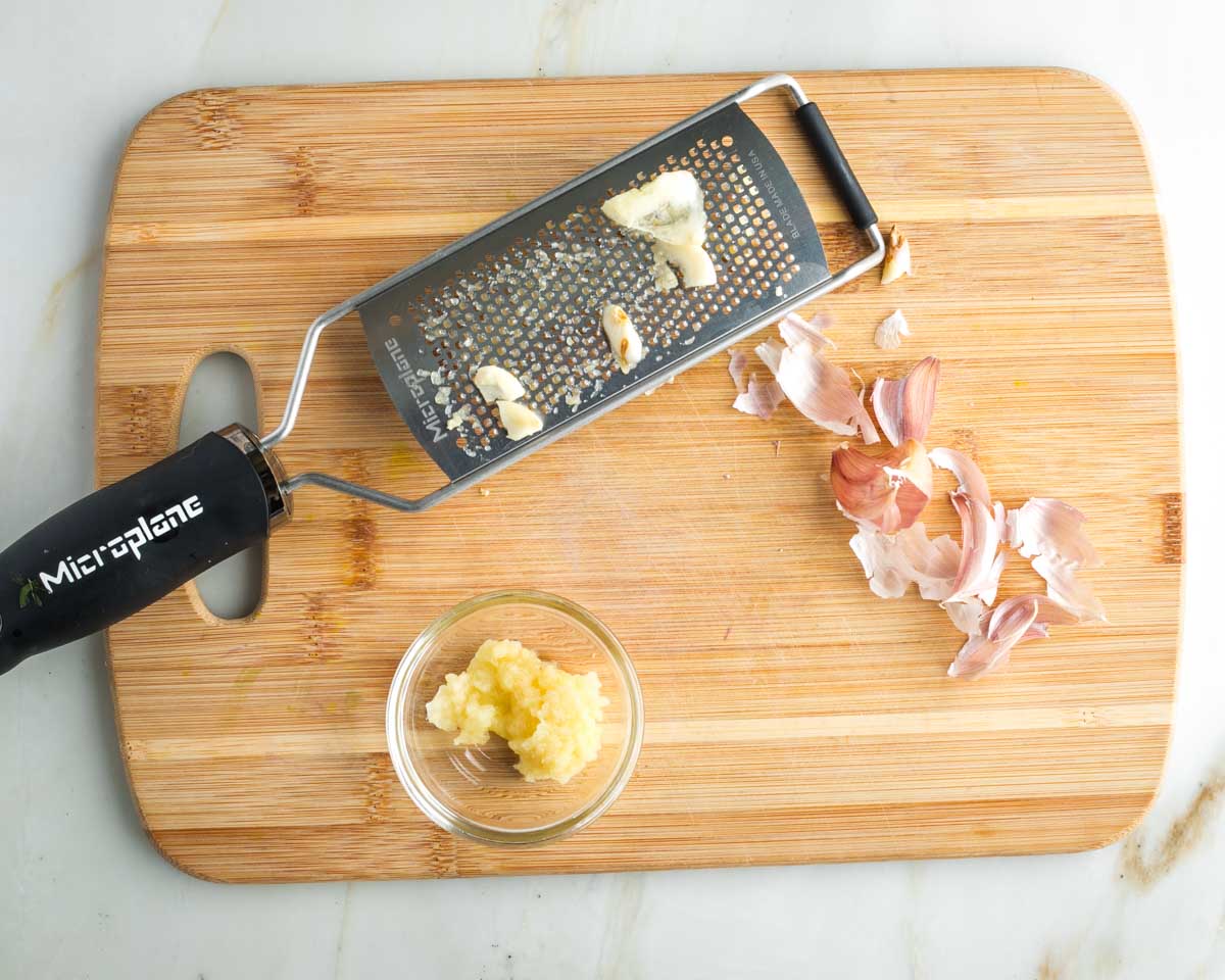 Peeling cloves of garlic and then grating on a microplane. 