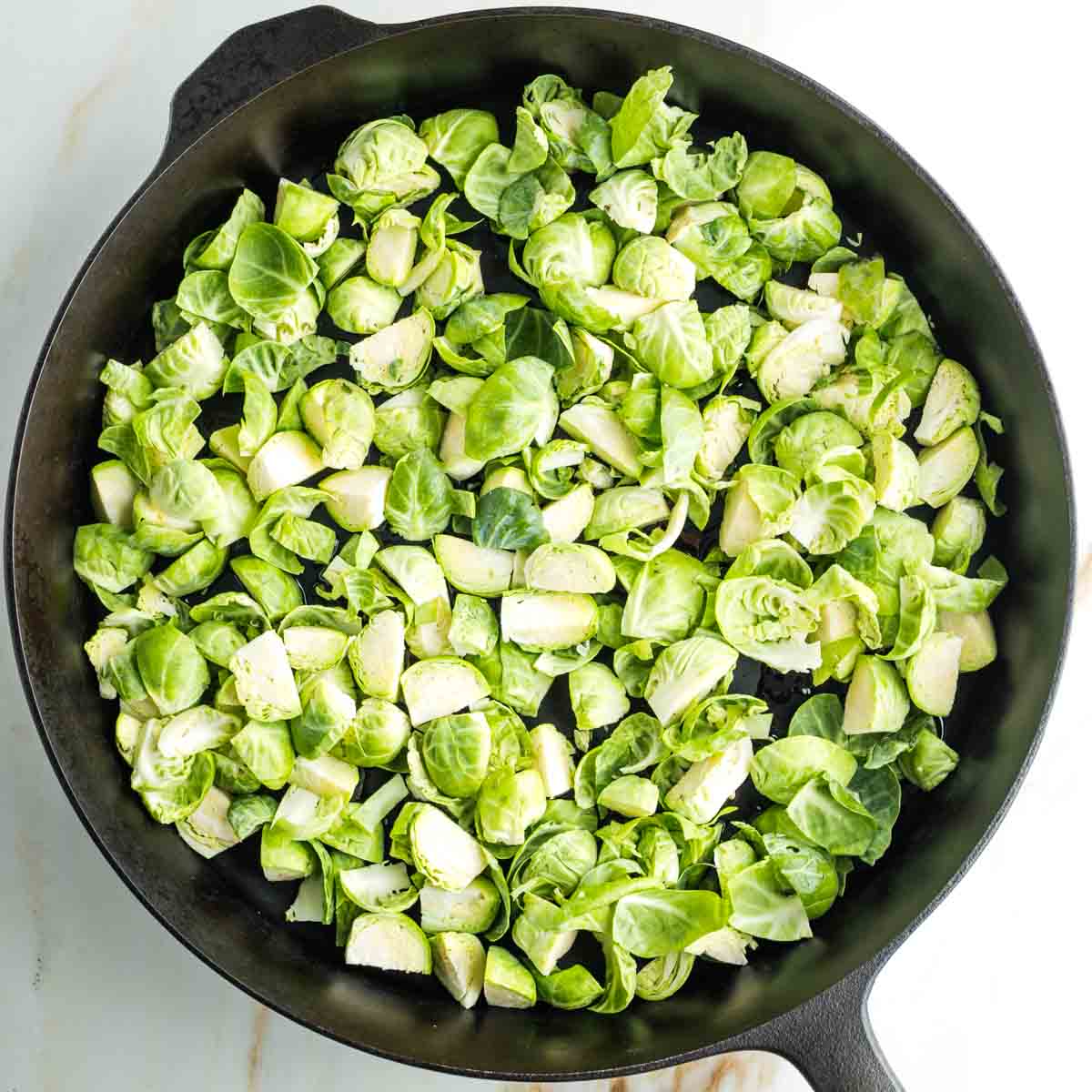 Quartered Brussels sprouts in a cast iron skillet. 