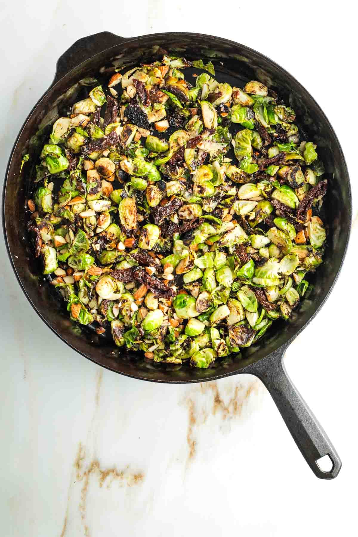 Crispy skillet cooked brussels sprouts with sun dried tomatoes and chopped almonds. 