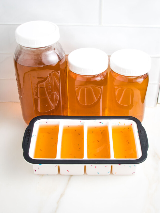 Different sized glass mason jars plus silicone ice cube trays filled with golden colored stock, ready for the freezer.