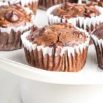 Chocolate muffin with chocolate chips in a white cupcake liner.
