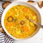 Large white bowl filled with thick and creamy red lentil soup that also has chunks of cauliflower and carrots.
