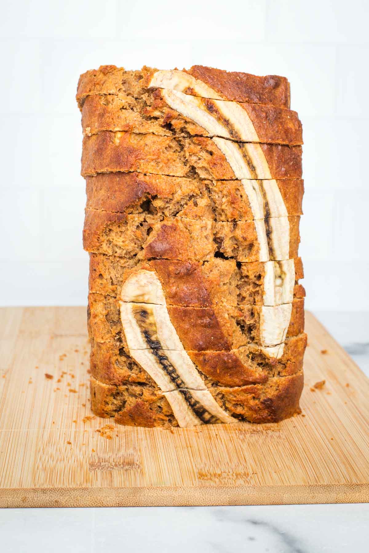 Banana bread, sliced thickly and stacked vertically to show the decorative banana slice on top. 