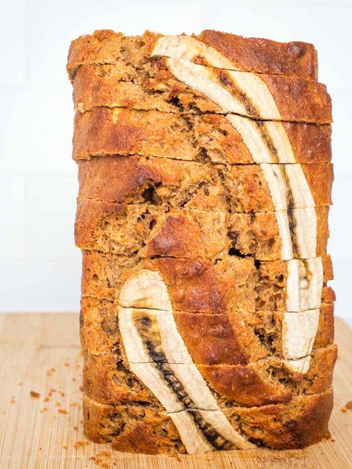 Slices of banana bread, stacked high with decorative banana slices on the edge.