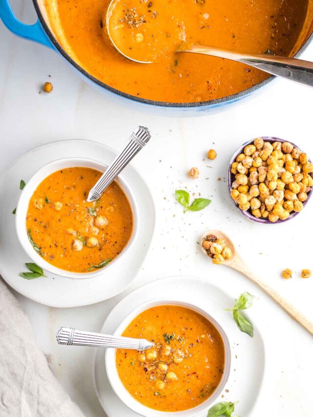 Bowls of creamy tomato soup with crunchy chickpeas and a bowl with more chickpeas.