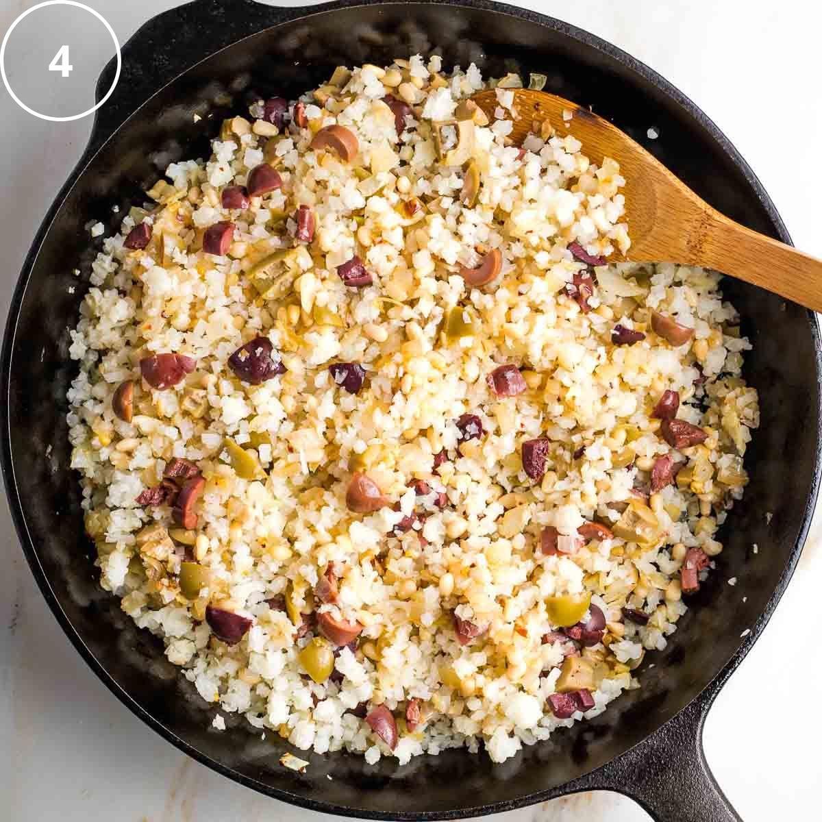 Step 4: Mediterranean cauliflower rice with olives and pine nuts in a cast iron pan.