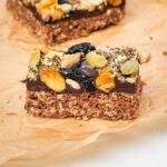 Side view of an oatmeal bar topped with chocolate and trail mix.