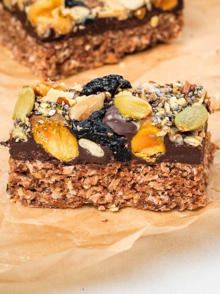 Side view of an oatmeal bar topped with chocolate and trail mix.