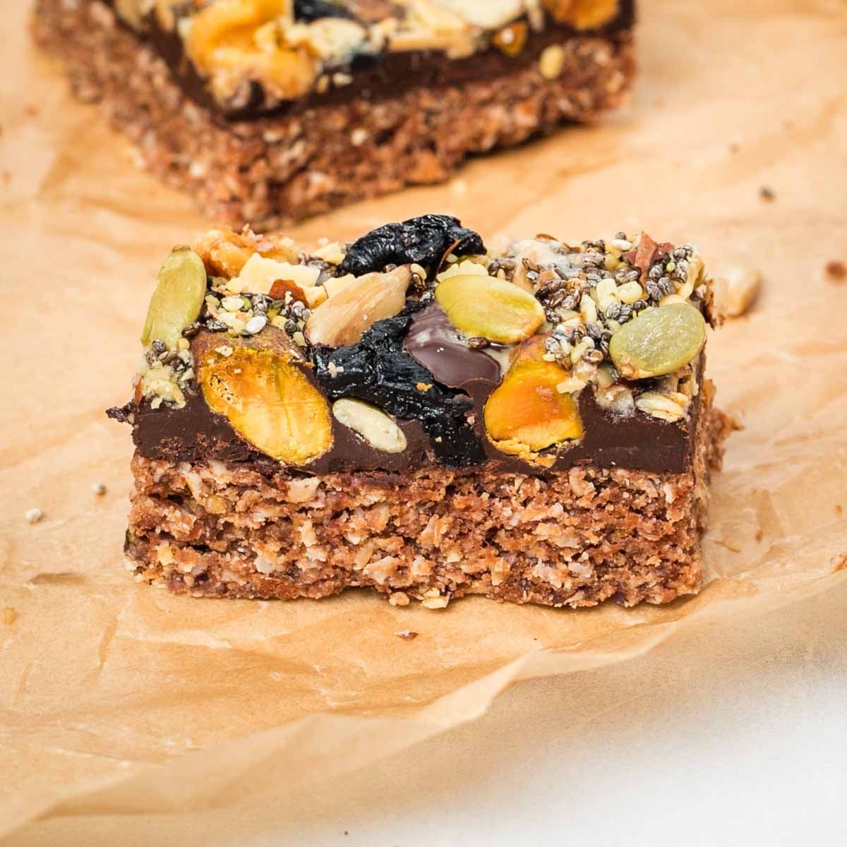 Side view of an oatmeal bar topped with chocolate and trail mix.