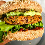 Veggie burger in a bun with lettuce, ketchup and guacamole.