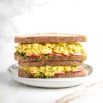 Vegan chicken salad sandwich with lettuce and sliced radishes on sourdough, stacked two high.