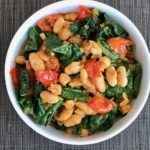 white bowl filled with cannelini beans, tomatoes and kale.