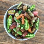 Snap peas, carrots, radishes in a white bowl.