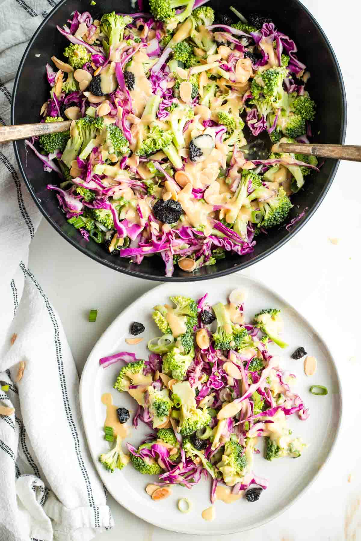 Broccoli salad with cabbage, almonds, scallions and miso dressing in a serving bowl and on a plate. 