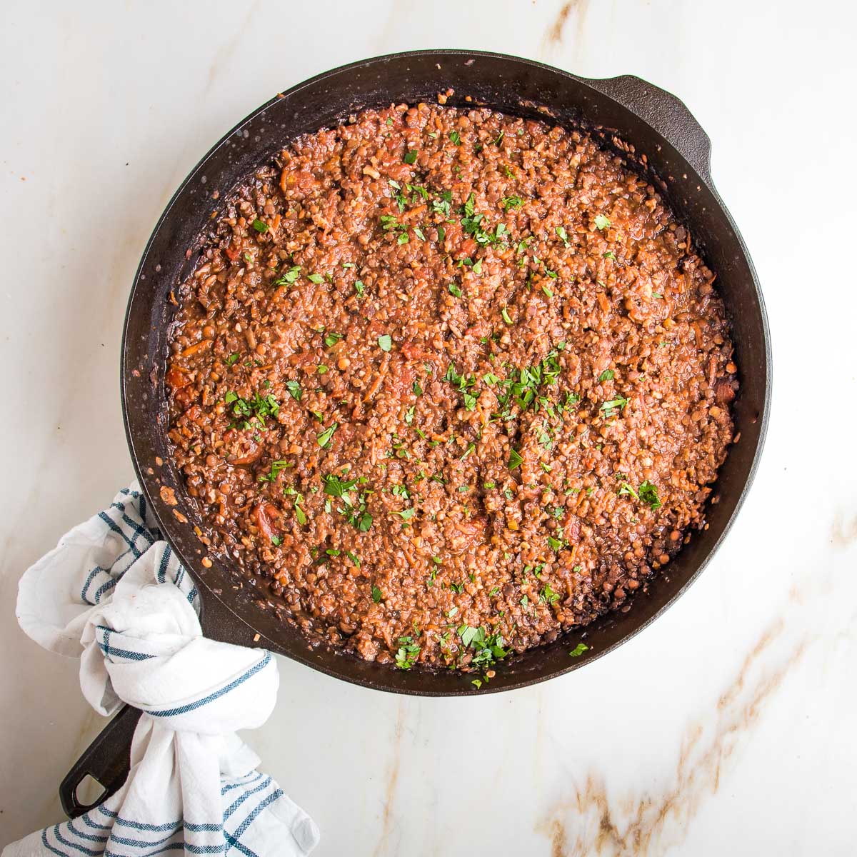 Vegan bolognese sauce inside a cast iron skillet, sprinkled with fresh parsley.