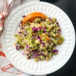 Colorful quinoa and riced broccoli salad with red cabbage and orange wedge.
