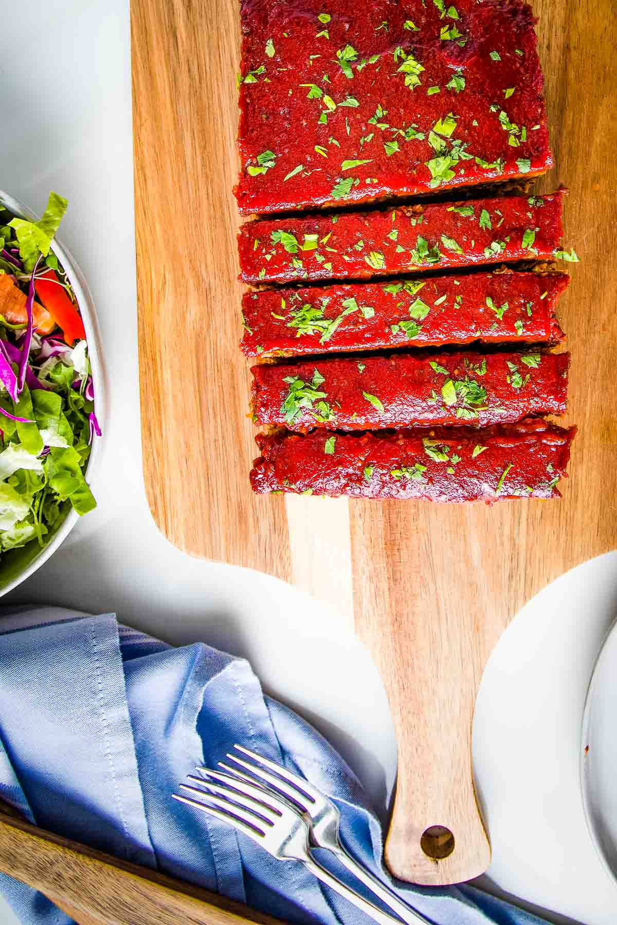 Meatloaf with tomato glaze, cut into slices, sprinkled with fresh herbs.