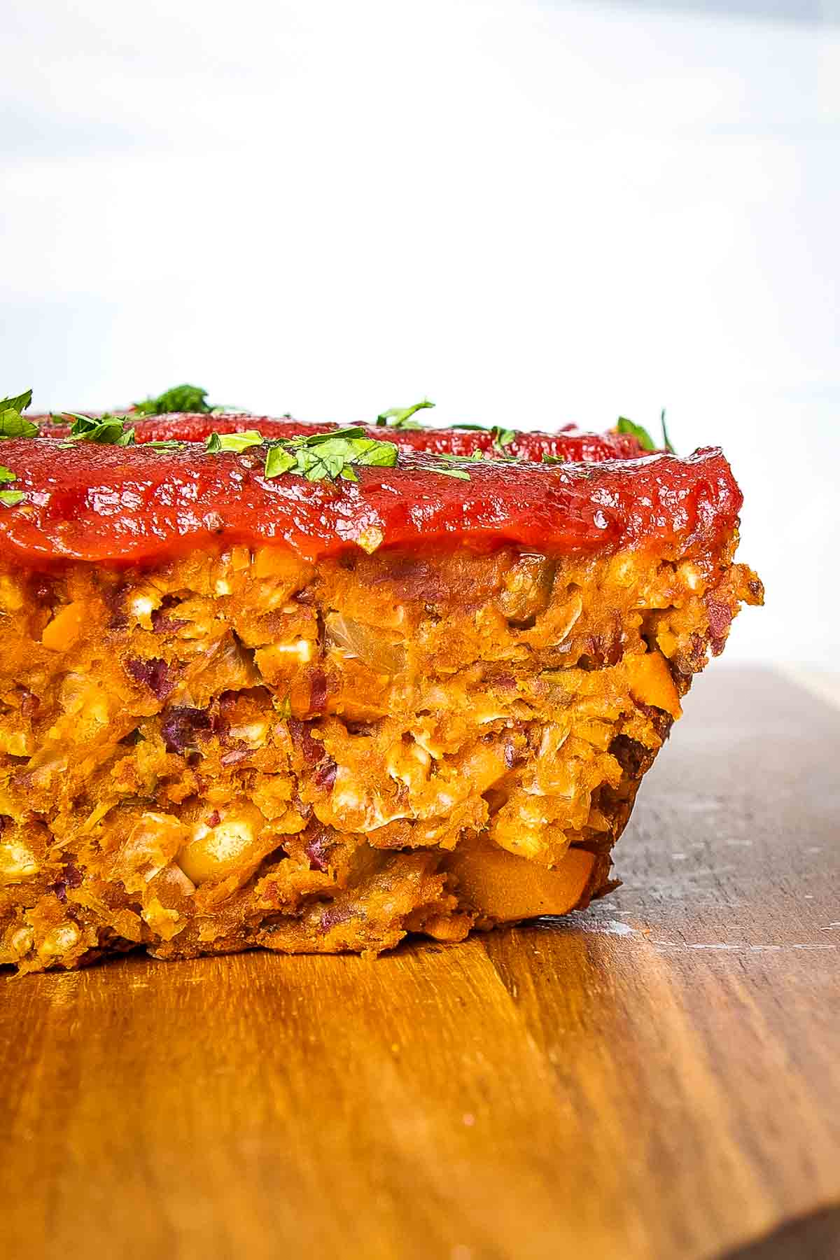Side view of a slice of vegan meatloaf with tomato glaze on top.