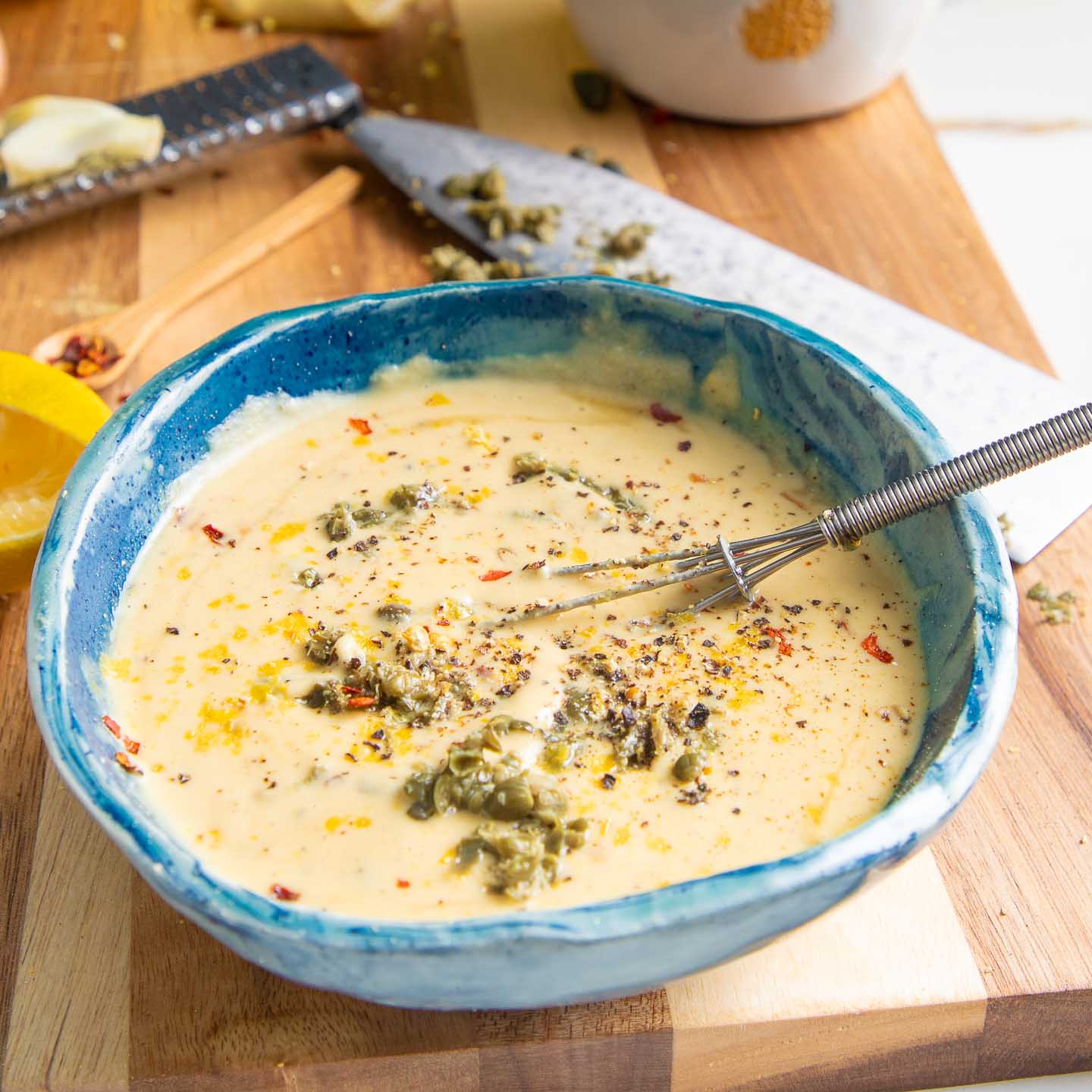 Bowl of caesar dressing with capers.
