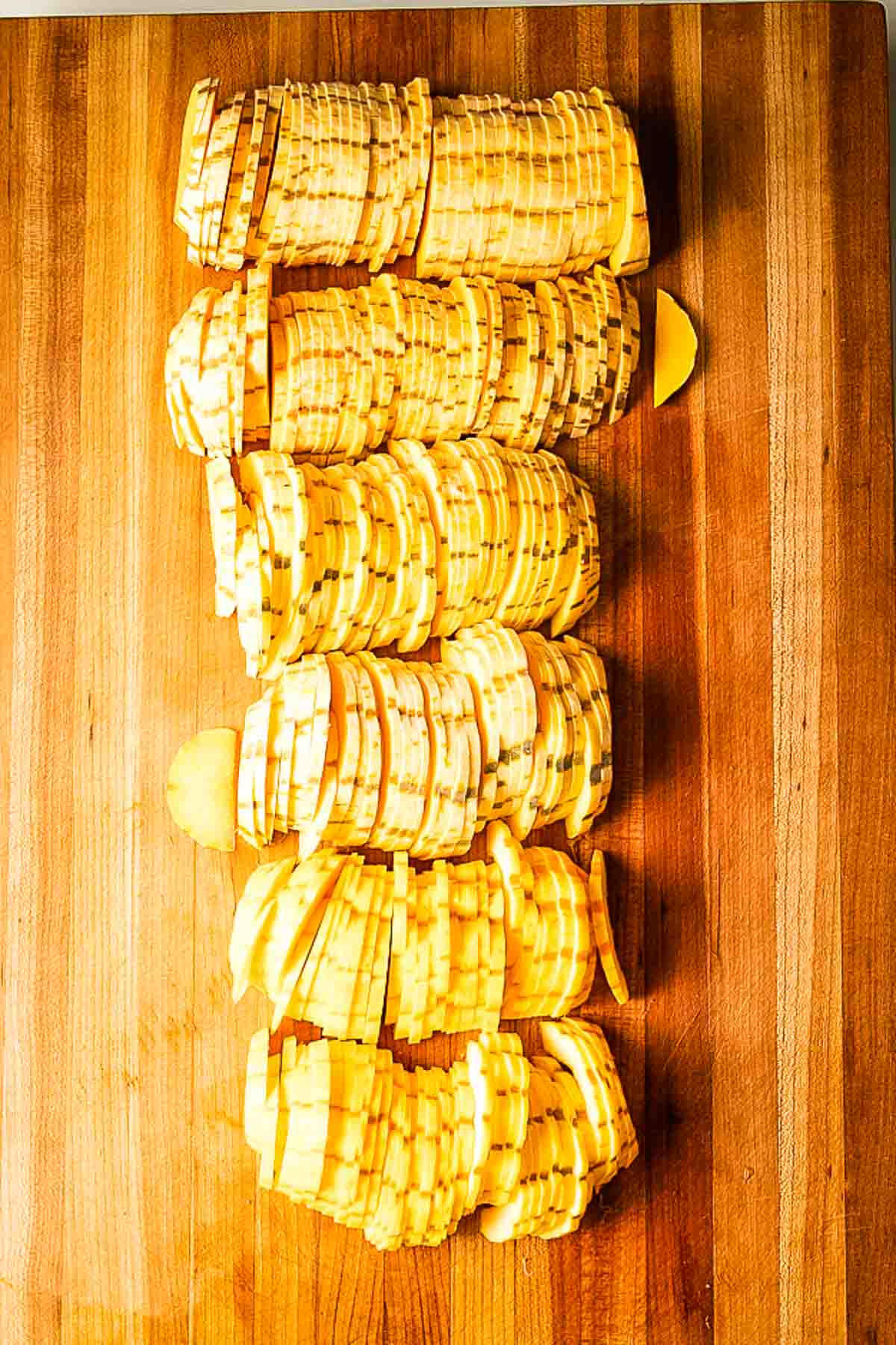 Cutting board filled with thin half moon slices of delicata squash.