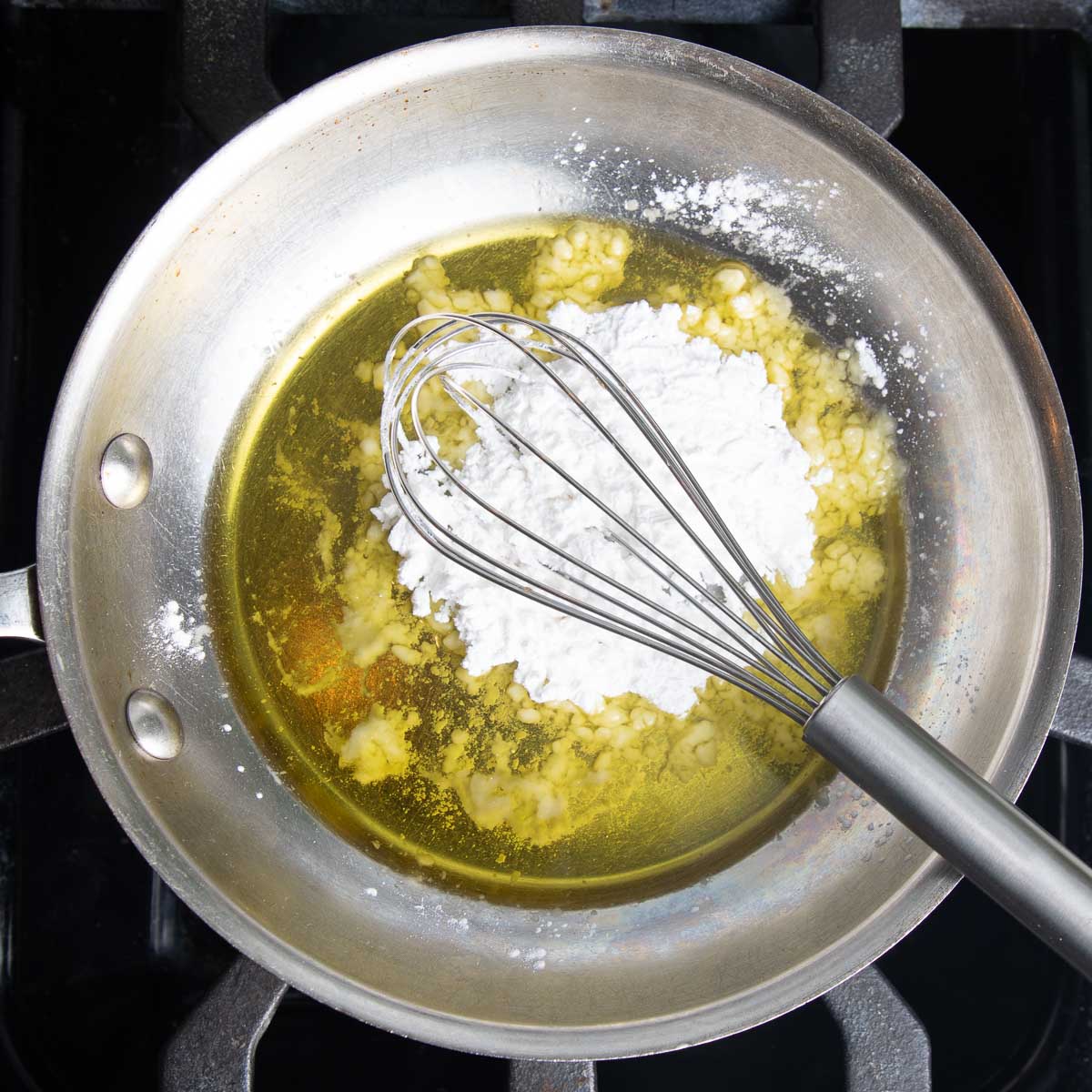 Whisking arrowroot powder into a skillet with olive oil. 