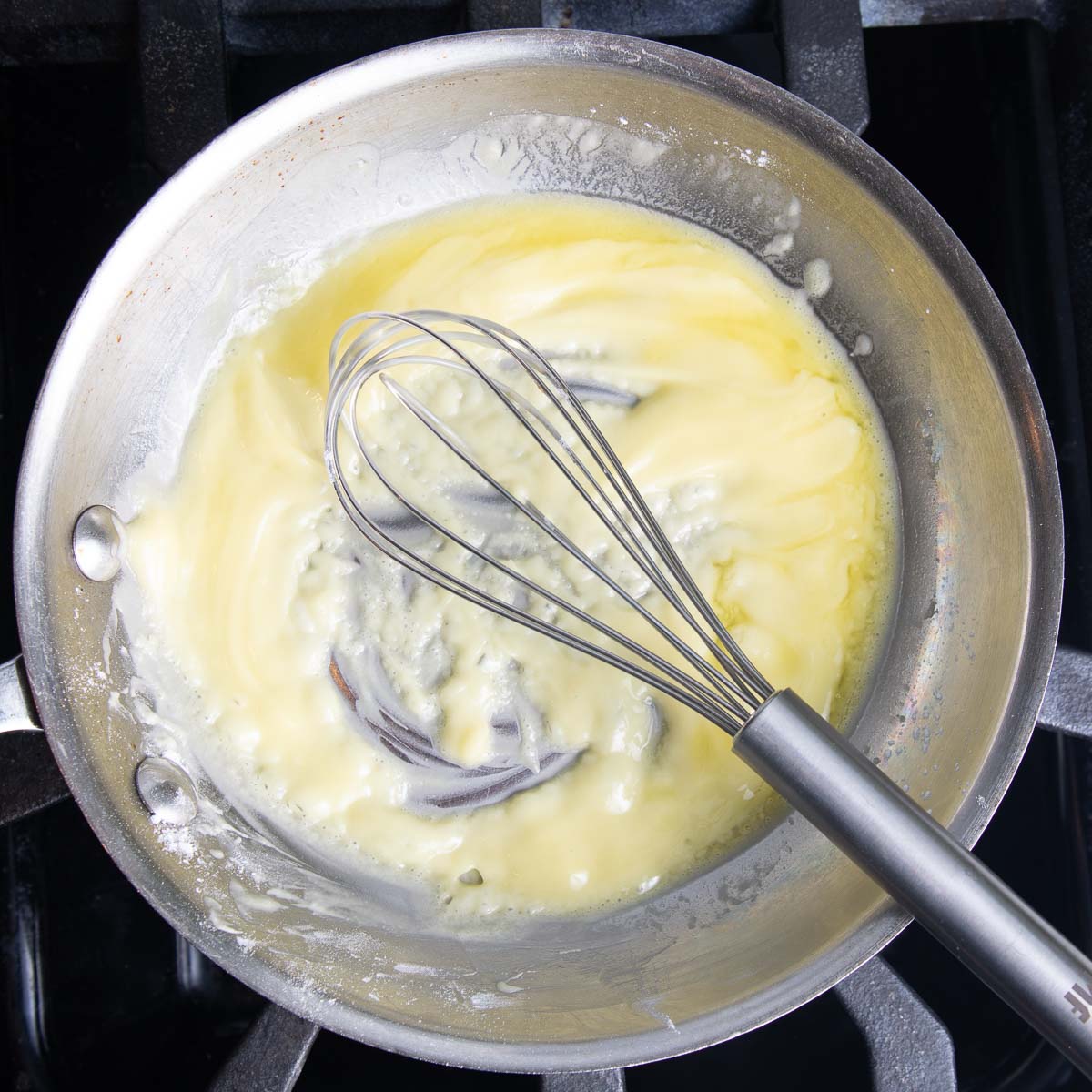 Whisking a roux of oil and arrowroot in a shallow fry pan.