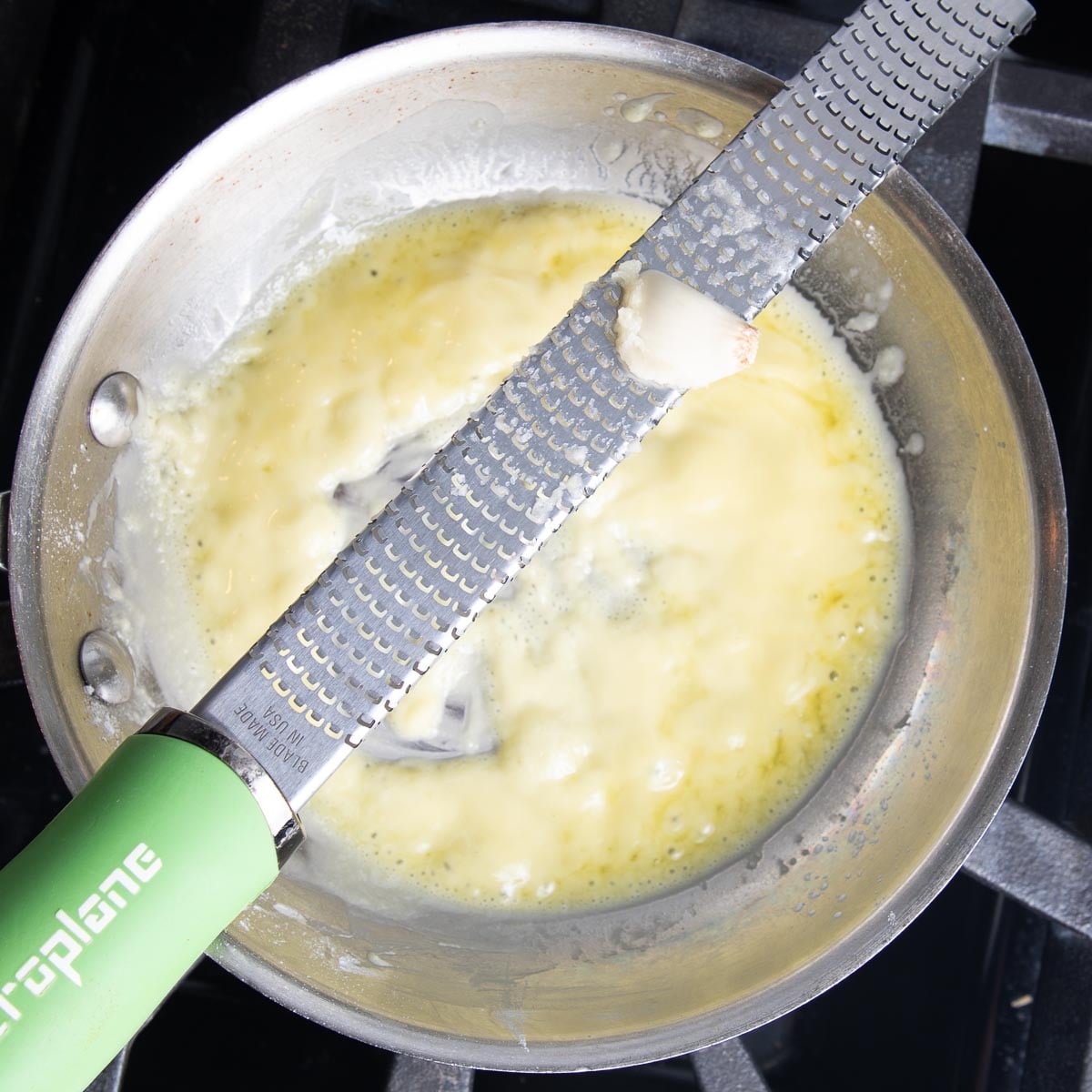 Grating garlic on a microplane directly over a skillet with a roux.