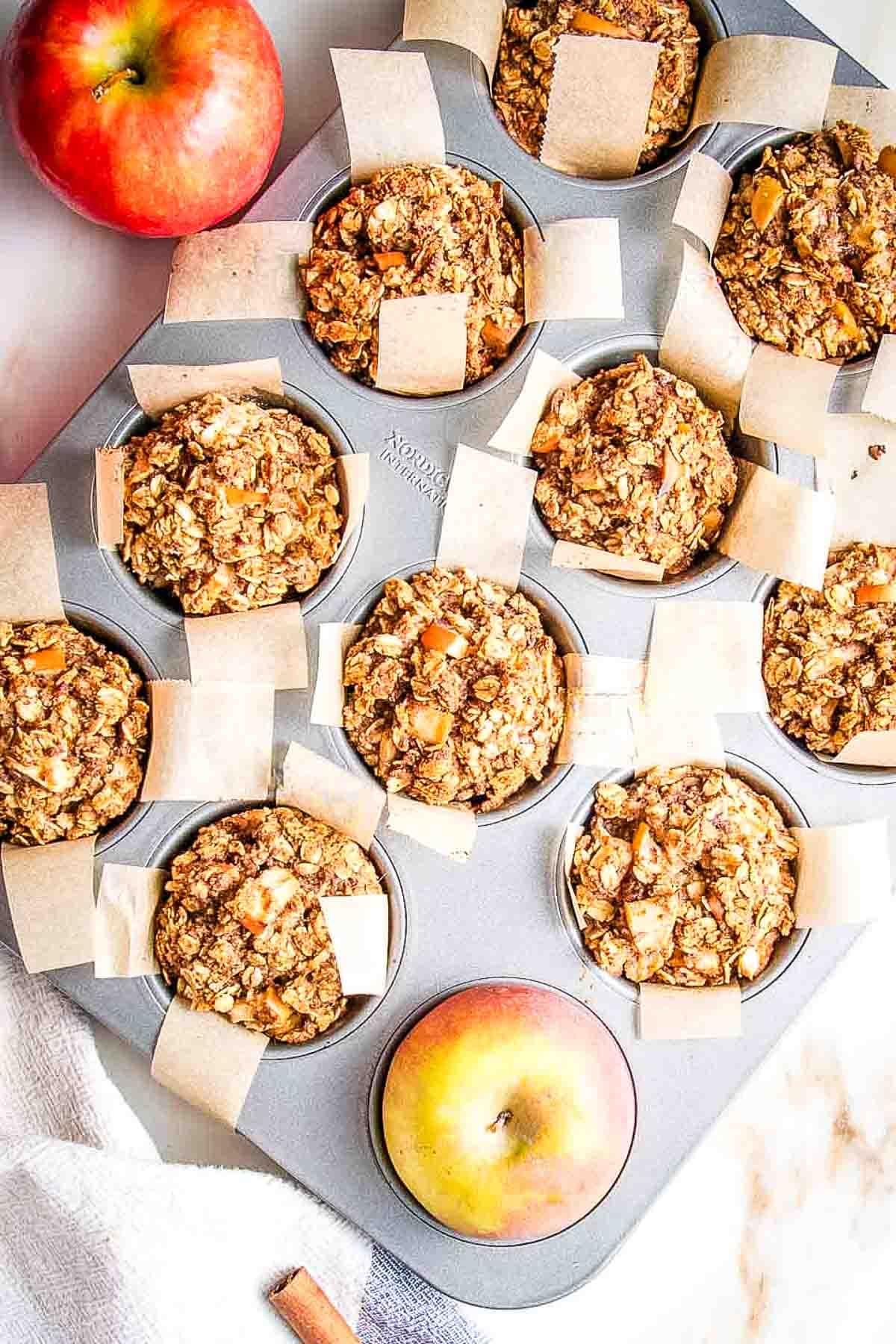 Chunks of apples baked into oatmeal muffins in a tin.
