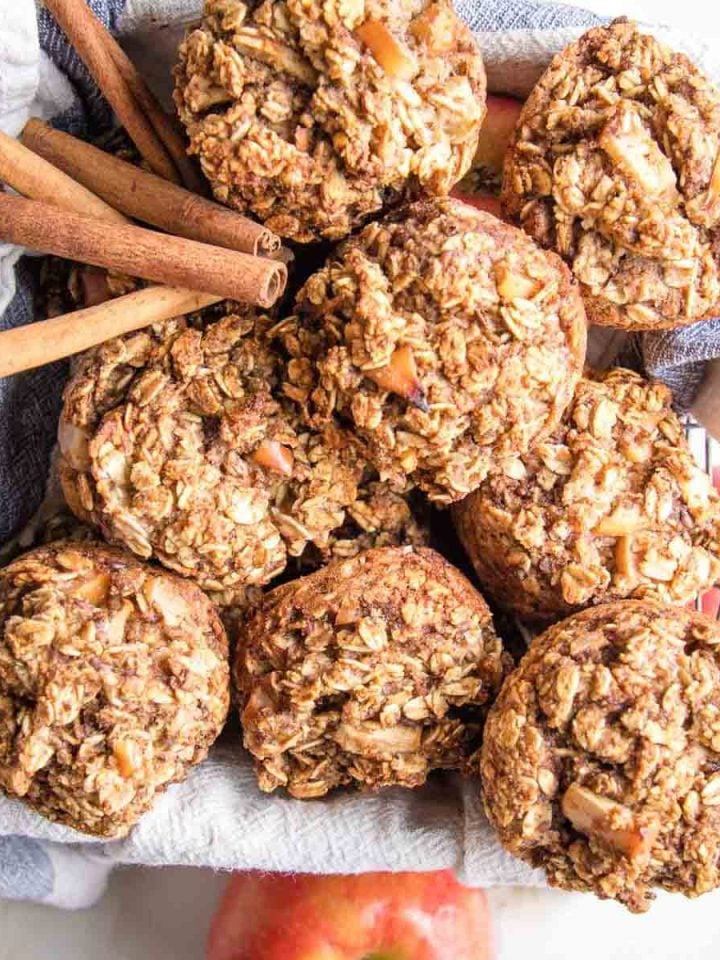Oatmeal apple muffins in a basket with cinnamon stick and apples around.