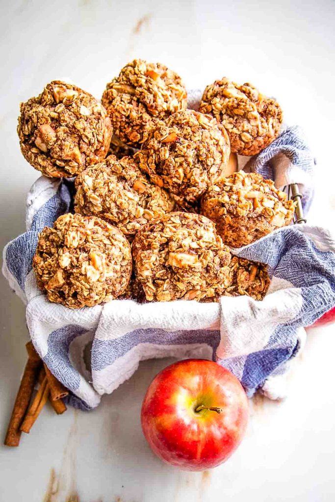 Basket of oatmeal apple muffins plus an apple and a few cinnamon sticks.
