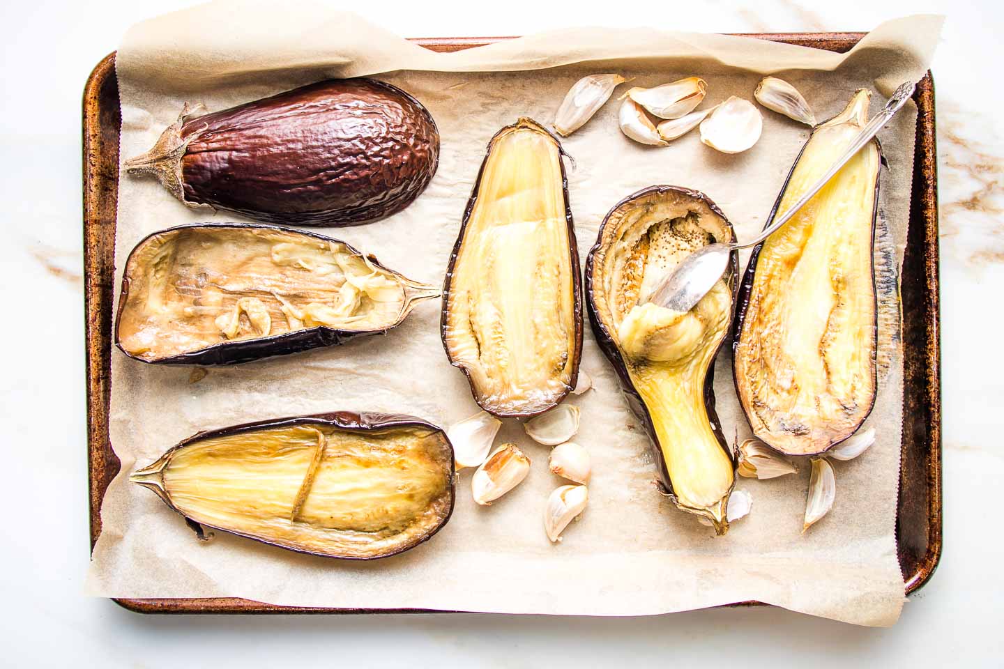 Scooping out the pulp of roasted eggplant with a spoon. 