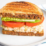 Side view of a vegan tuna sandwich with lettuce and tomatoes on toast.