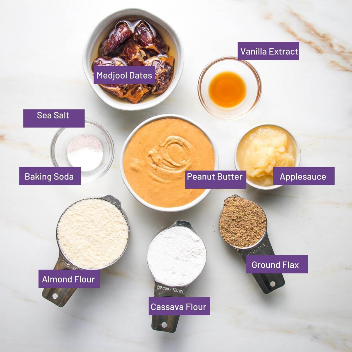 Labeled ingredients for peanut butter cookies with peanut butter, dates, applesauce, flax seeds, almond flour, cassava flour and baking powder. 
