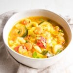 White bowl, filled with chunky veggies in a brothy soup.