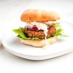 Veggie burger in a bun with lettuce and sauce dripping down the side.