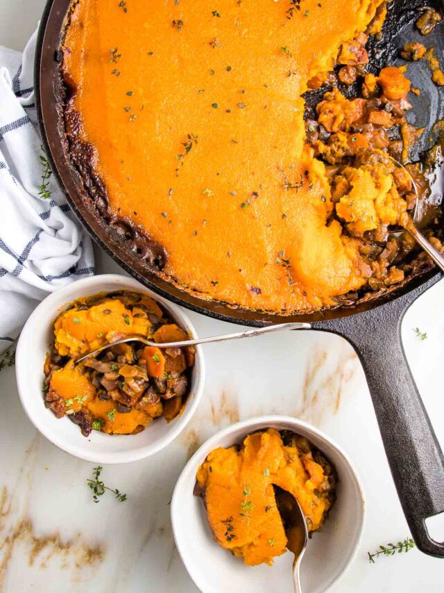 Cast iron skillet filled with lentil shepherds pie topped with sweet potato mash. Two small bowls with servings of vegan shepherd's pie on the bottom left of photo.