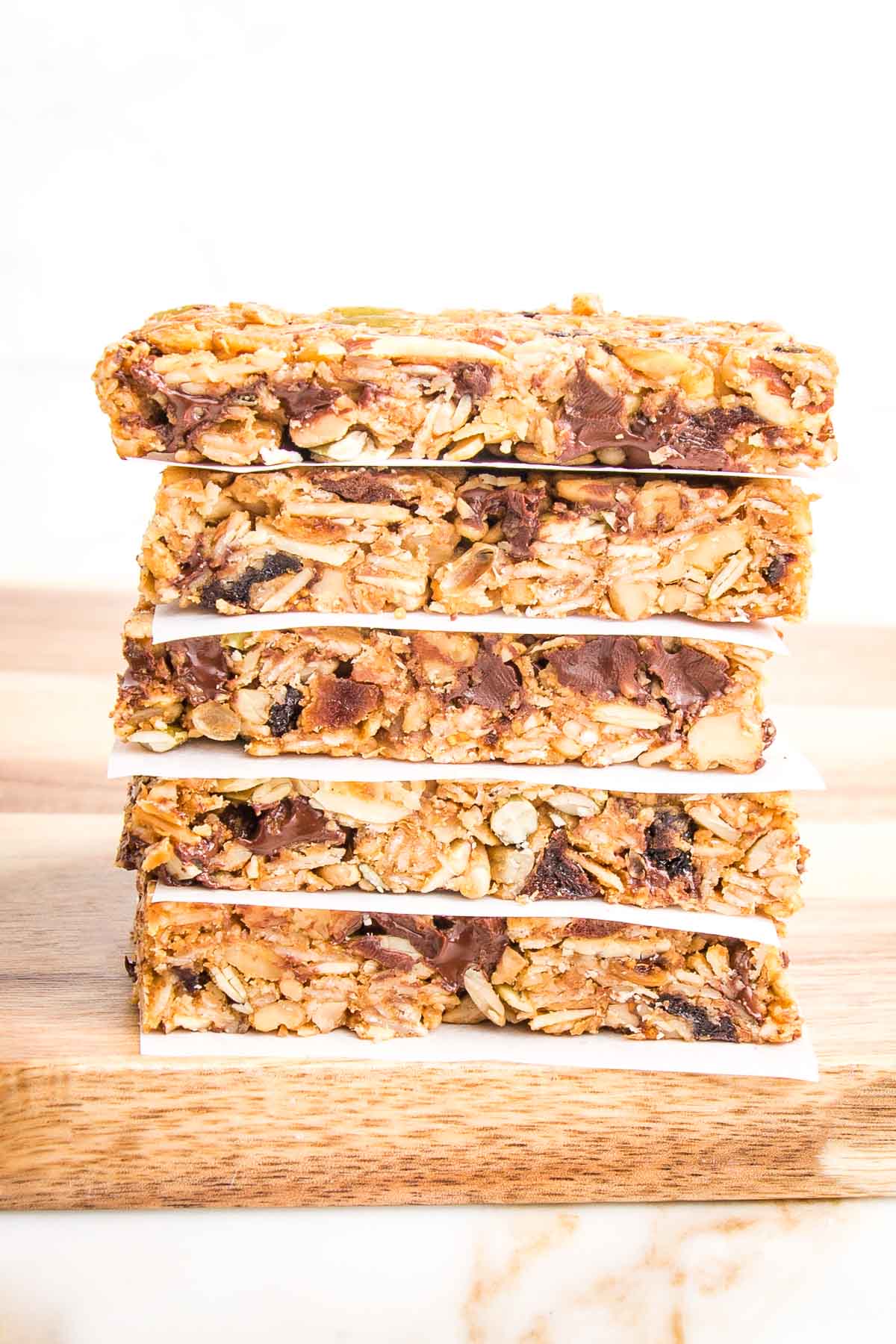 Stack of crunchy granola bars, separated by parchment paper.