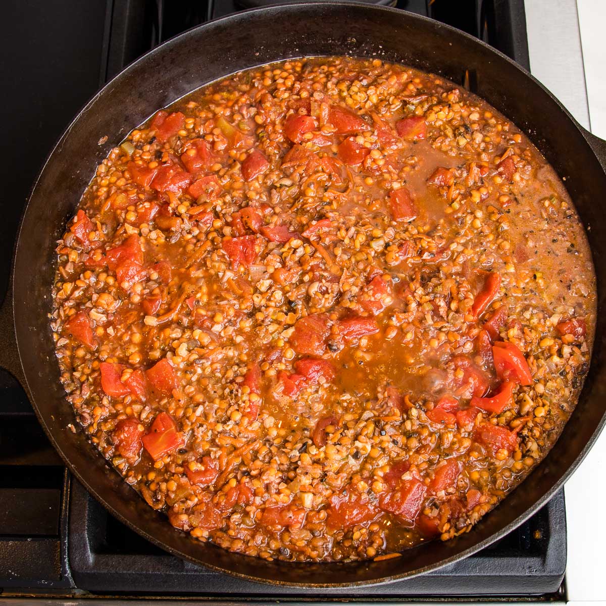 Chunky vegan bolognese simmering inside a cast iron skillet