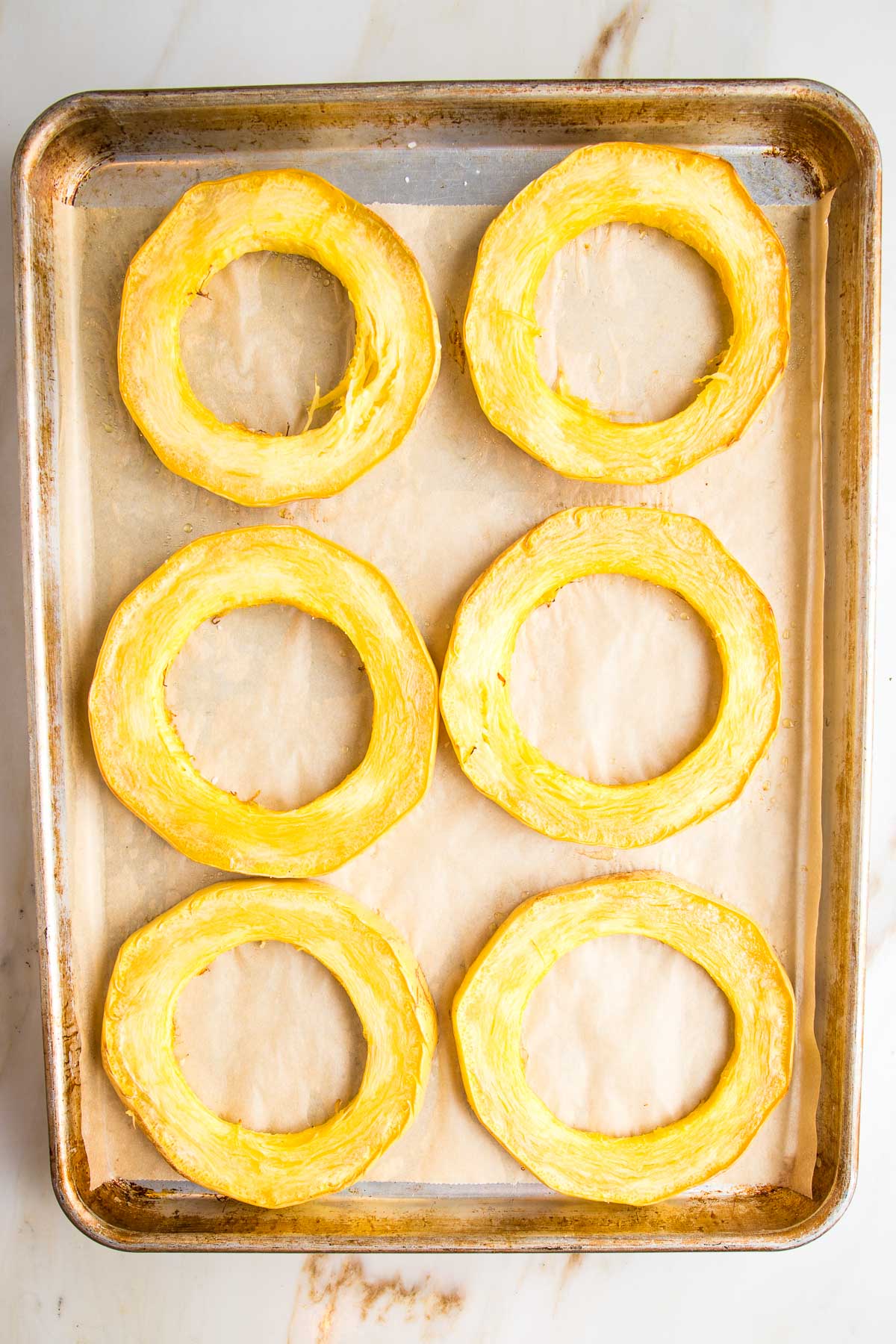 Roasted spaghetti squash rings on a parchment lined baking tray.