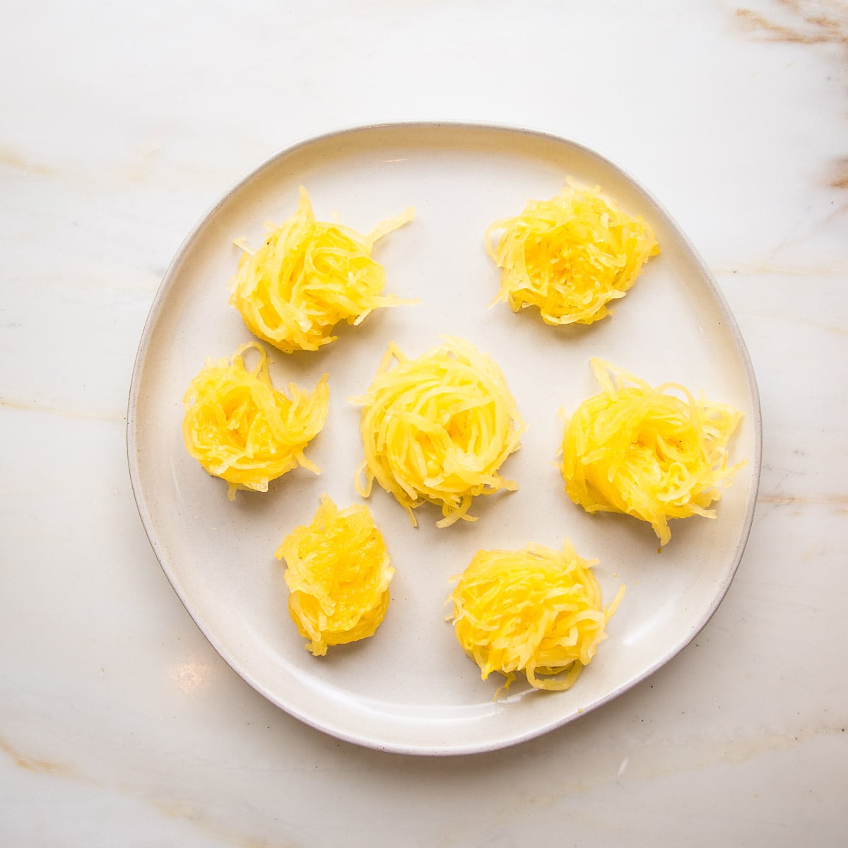 White rimmed plate with twirelled sections of spaghetti squash