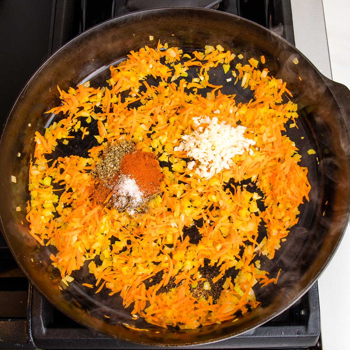 sauteed carrots, onions and celery, then spices and garlic are added to cast iron skillet.