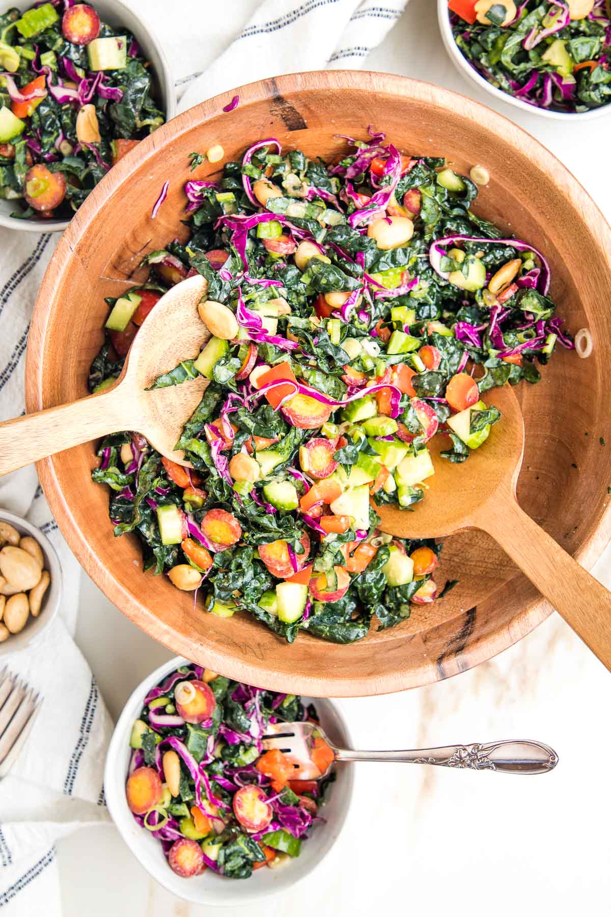Colorful chopped tuscan kale salad with miso dressing in a wooden bowl.