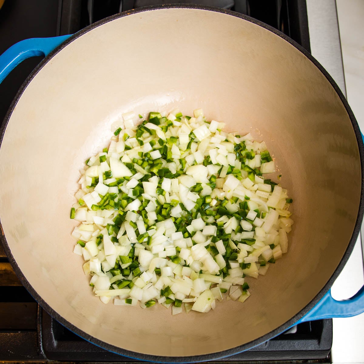 blue dutch oven with jalapenos and onions sauteeing