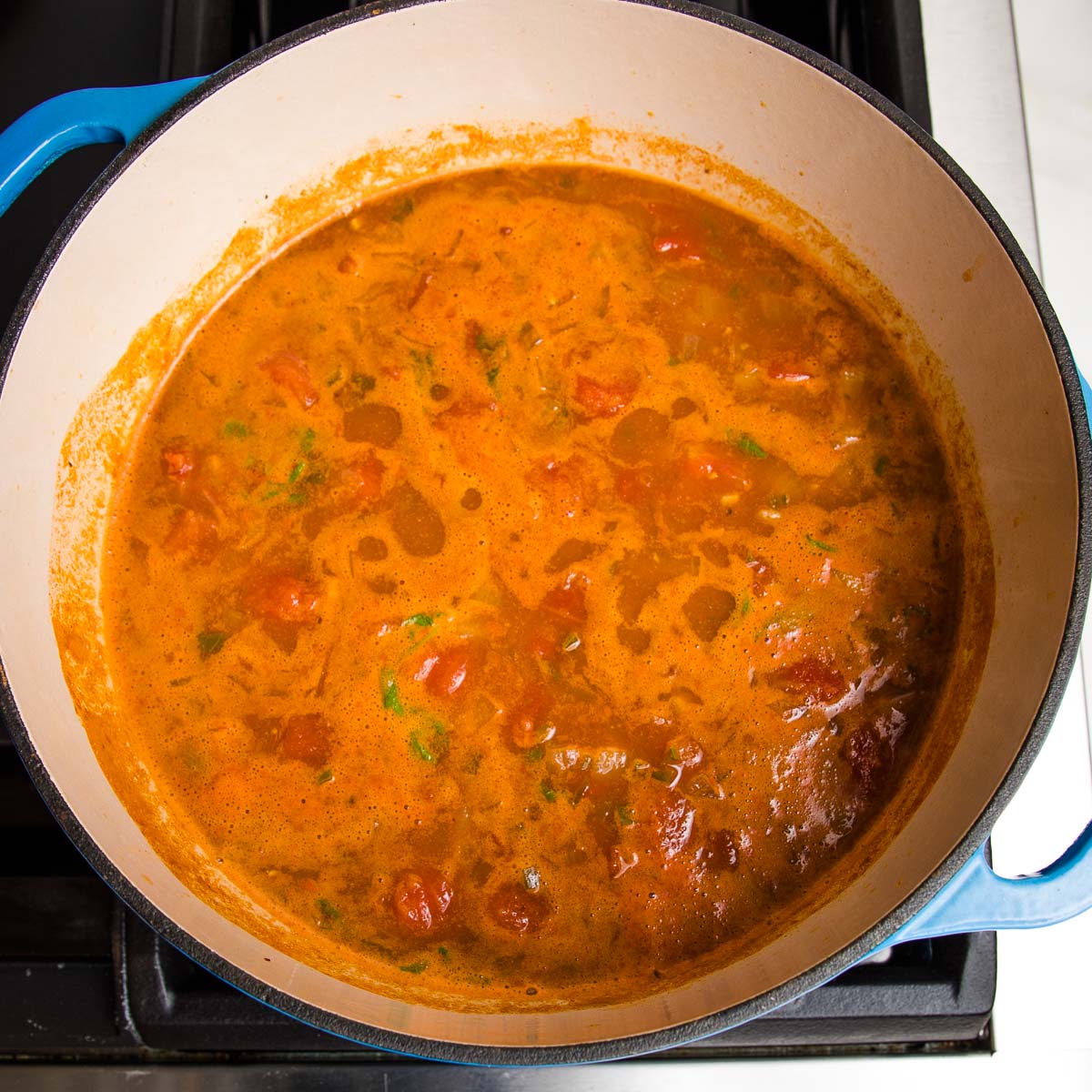 taco soup simmering on the stove in a dutch oven.